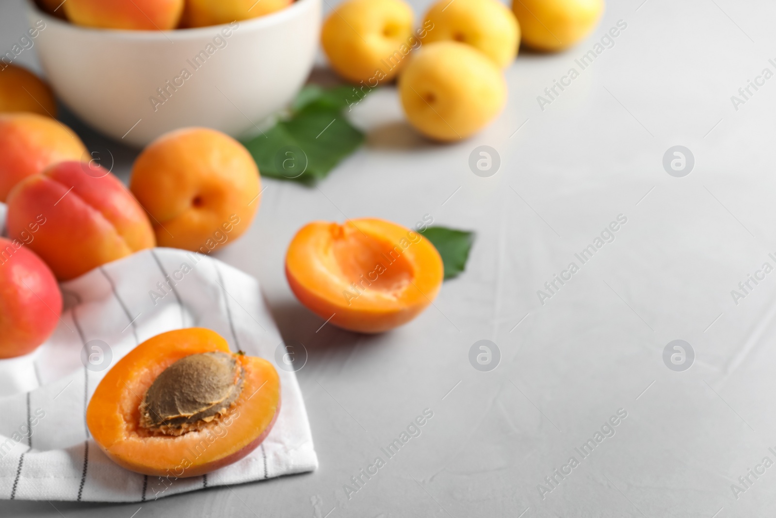 Photo of Fresh ripe apricots on light grey table. Space for text