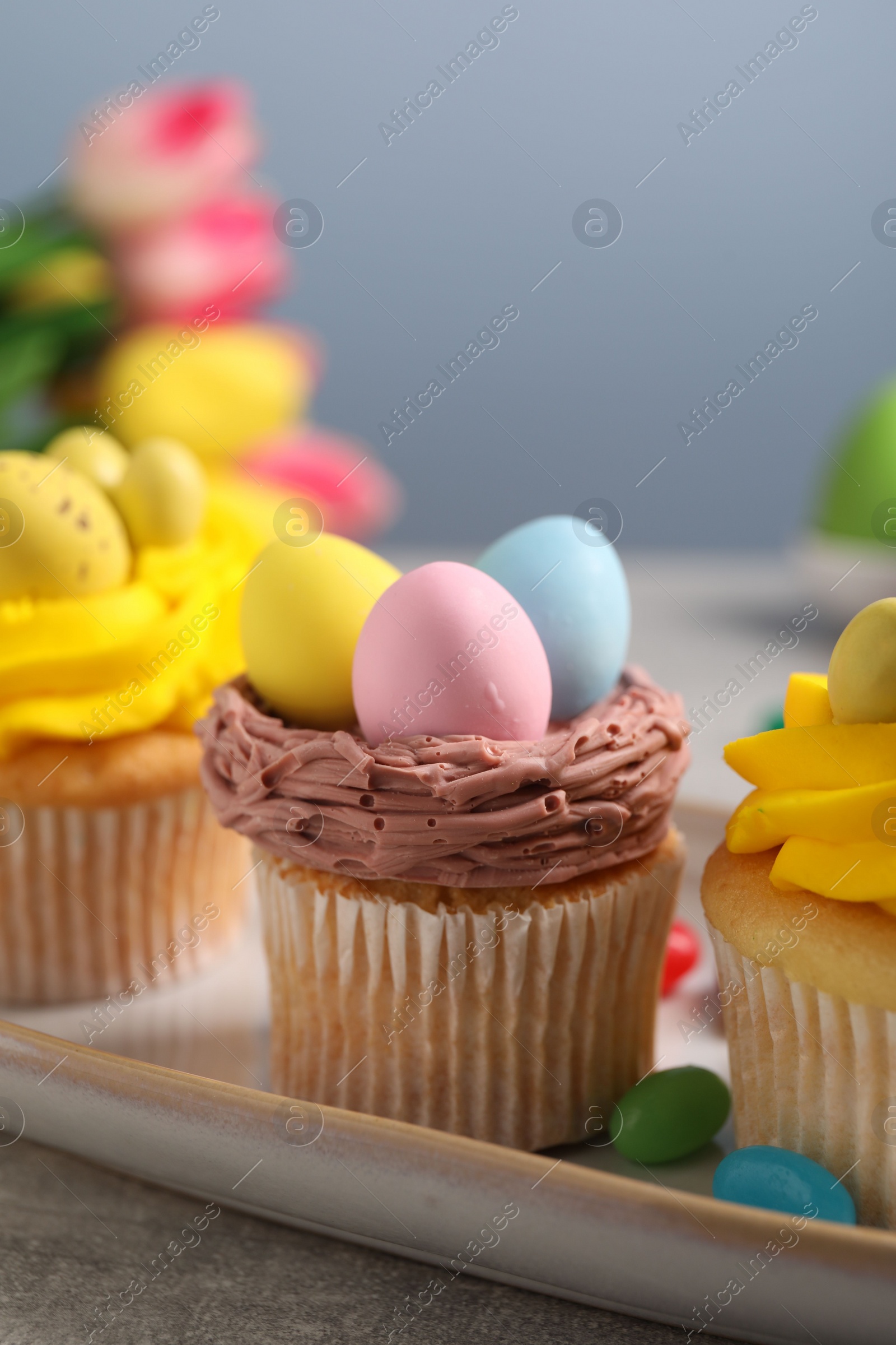 Photo of Tasty decorated Easter cupcakes on grey table, closeup