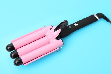 Photo of Modern triple curling iron on light blue background