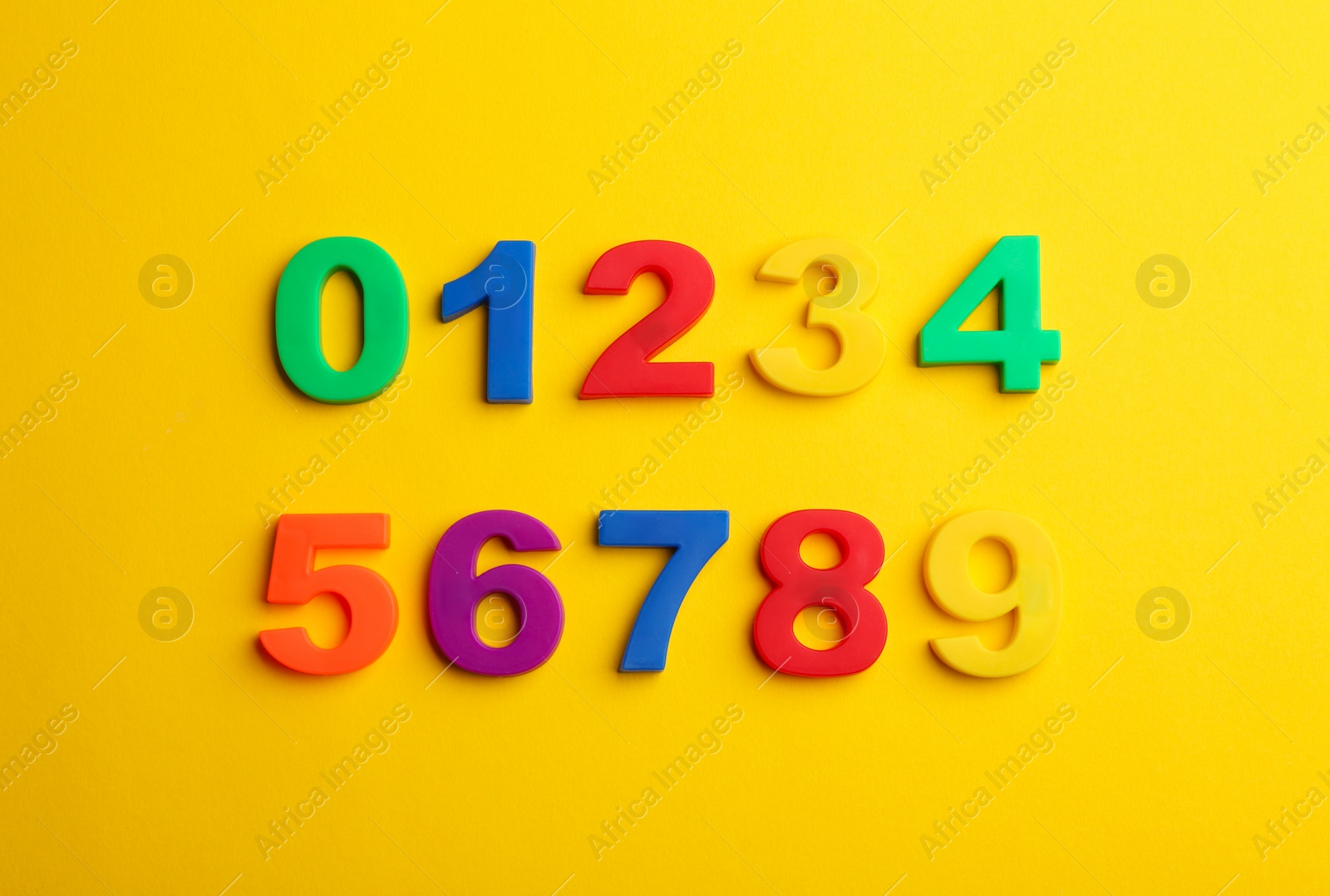 Photo of Colorful magnetic numbers on yellow background, flat lay