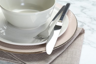 Photo of Clean plates, bowl, cutlery and napkin on table, closeup