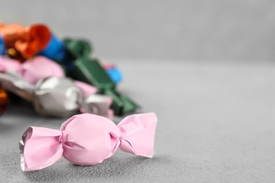 Candies in colorful wrappers on grey table, closeup. Space for text