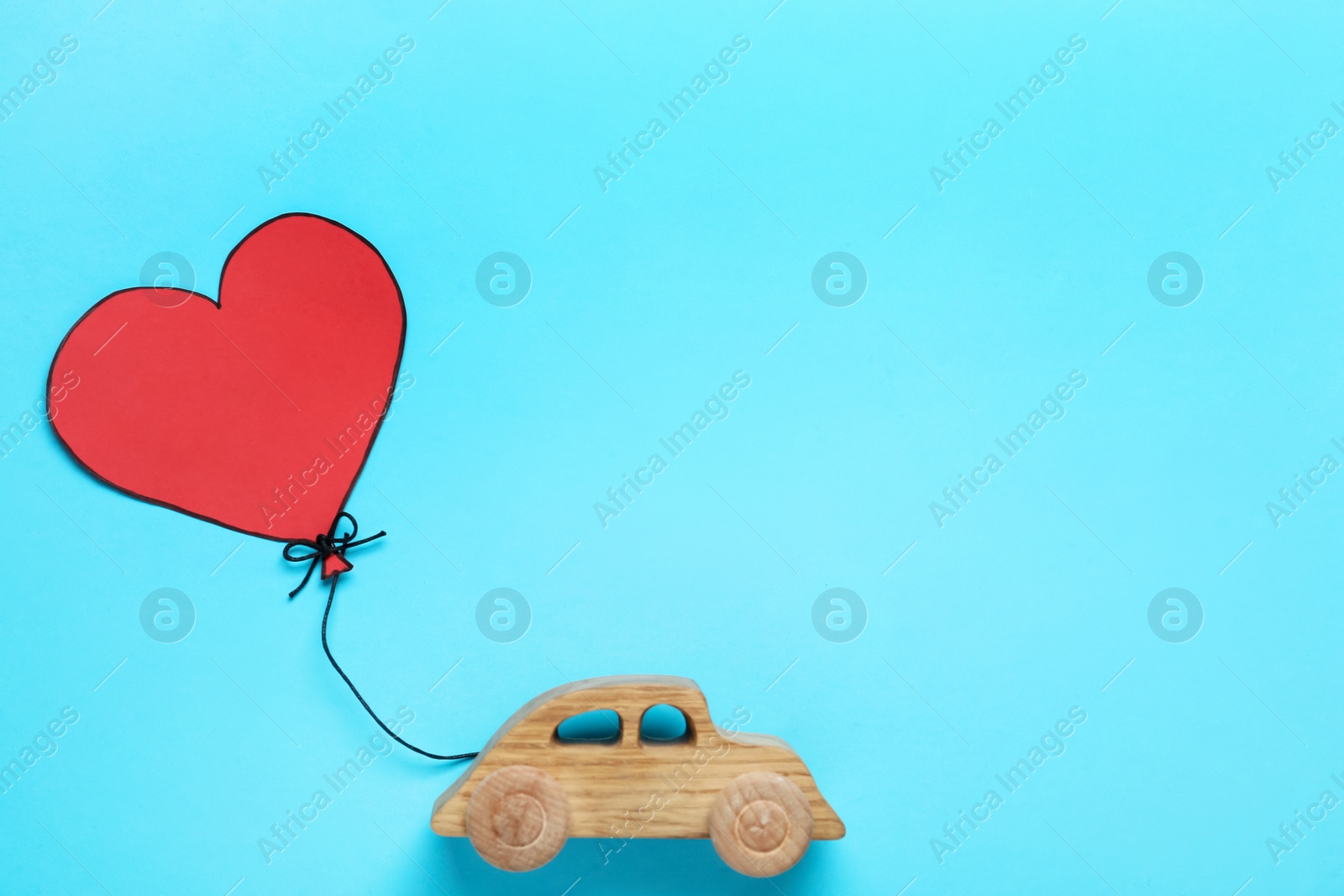 Photo of Wooden car, paper heart and space for text on light blue background, flat lay. Valentine's Day