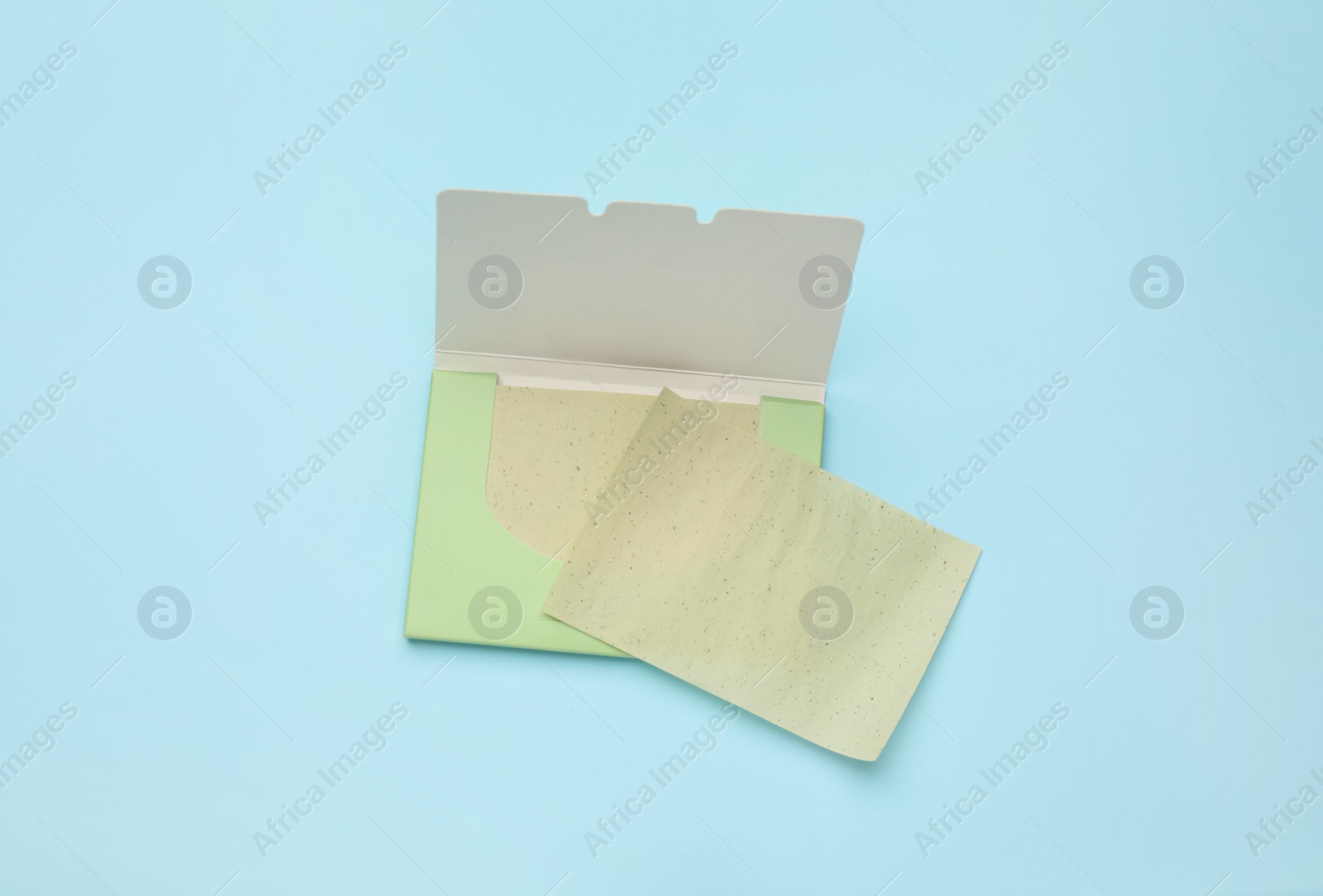 Photo of Facial oil blotting tissues on light blue background, flat lay. Mattifying wipes