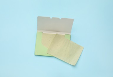 Facial oil blotting tissues on light blue background, flat lay. Mattifying wipes