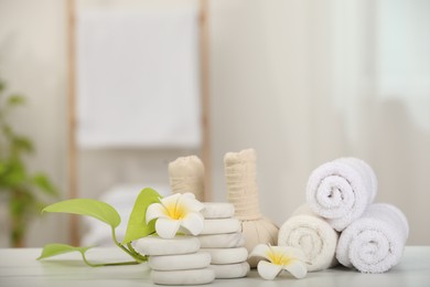 Composition with different spa products and plumeria flowers on white marble table indoors