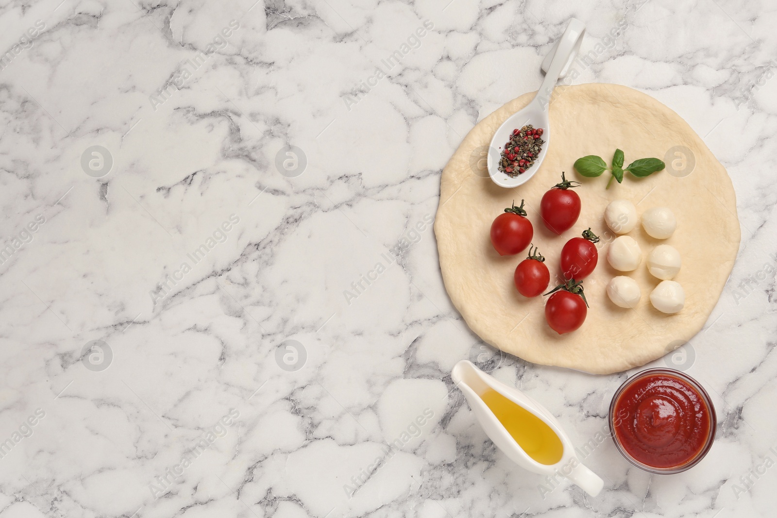 Photo of Raw pizza dough and other ingredients on white marble table, flat lay. Space for text