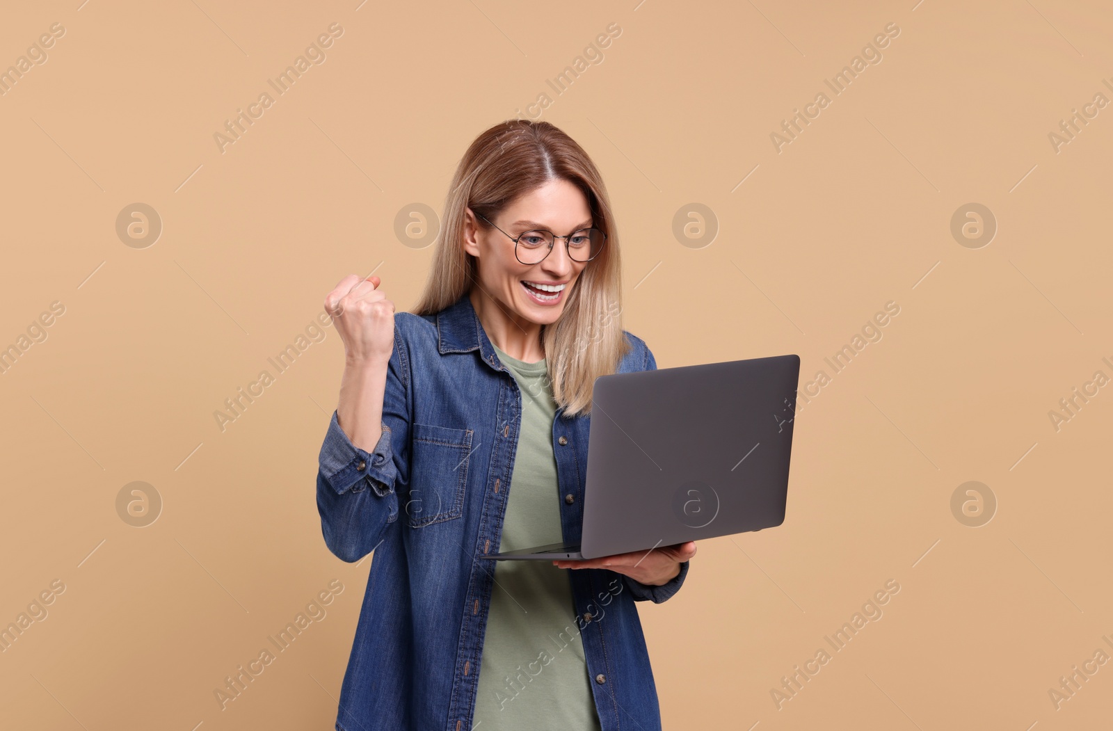 Photo of Emotional woman with laptop on beige background