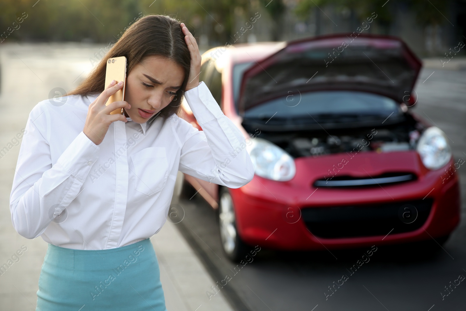 Photo of Stressed woman talking on phone near broken car outdoors