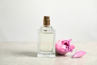 Photo of Bottle of perfume and beautiful rose on light table