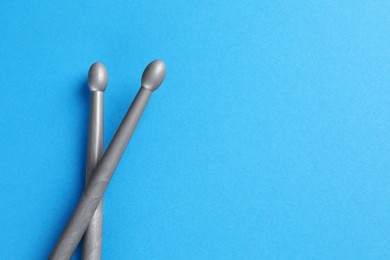 Photo of Two gray drum sticks on light blue background, top view. Space for text