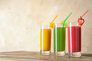 Photo of Three glasses of different juices with straws on table. Space for text