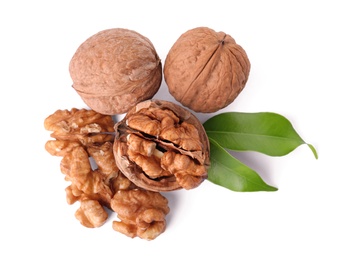 Walnuts in shell, kernels and green leaves on white background, top view