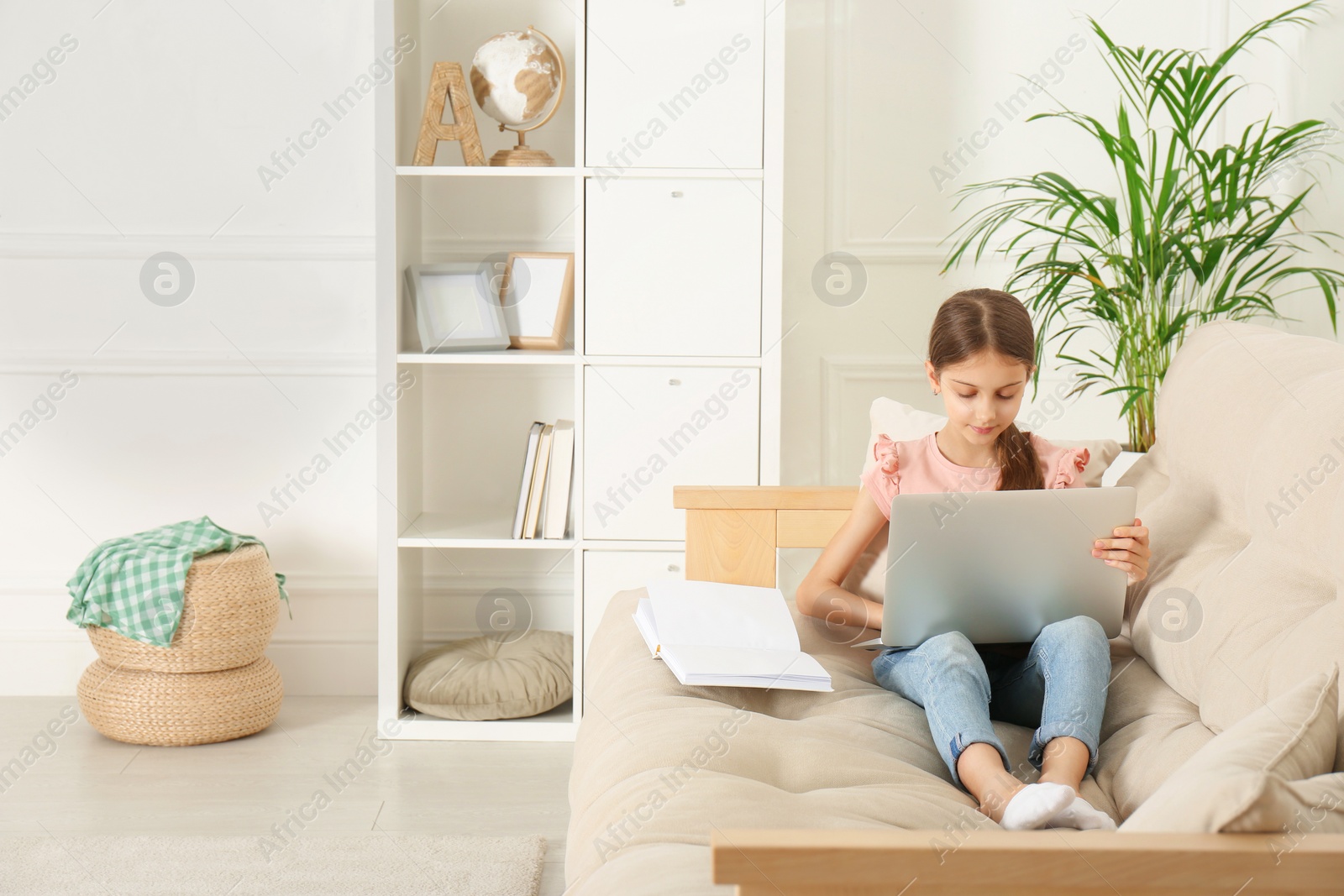 Photo of Girl with laptop and book on sofa at home