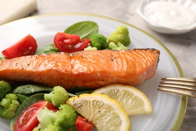 Photo of Healthy meal. Piece of grilled salmon, vegetables, lemon and spinach on table, closeup