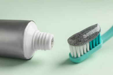 Photo of Brush and tube with charcoal toothpaste on white background, closeup