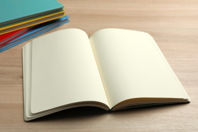 Photo of Open notebook and stack of planners on wooden table