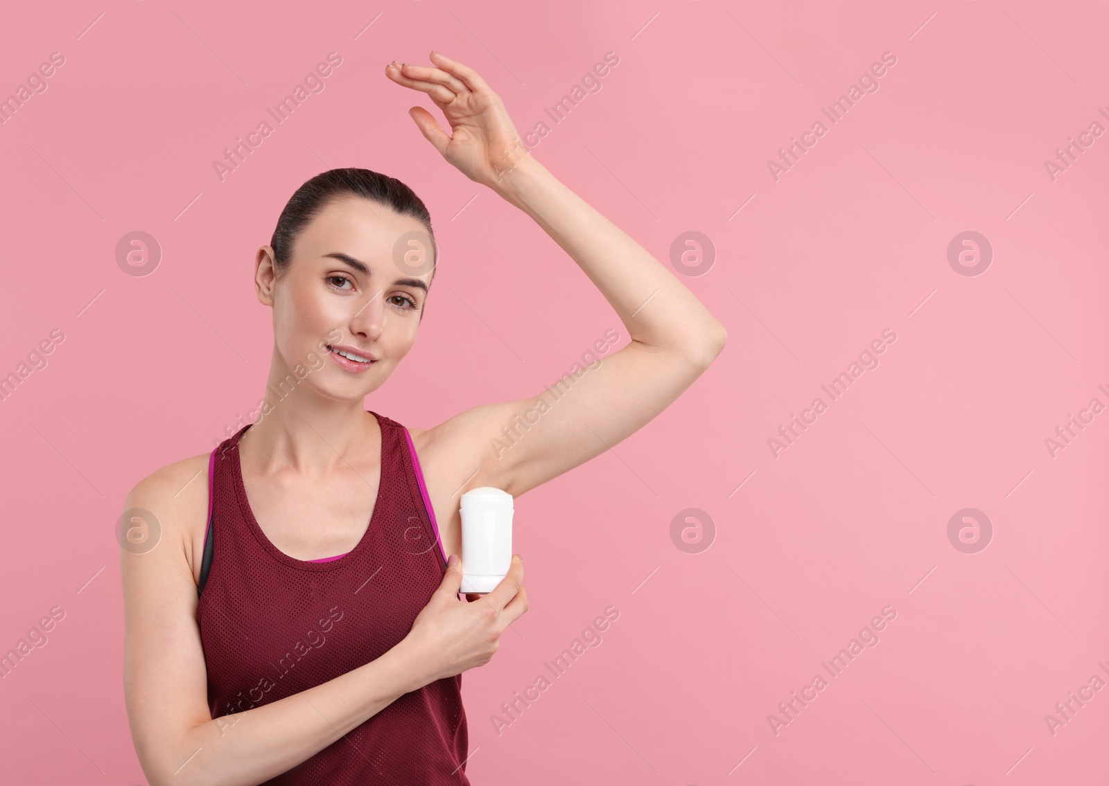 Photo of Beautiful woman applying deodorant on pink background, space for text