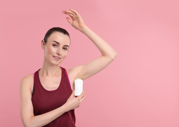 Photo of Beautiful woman applying deodorant on pink background, space for text