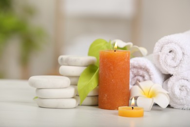 Composition with different spa products and burning candles on white table, closeup