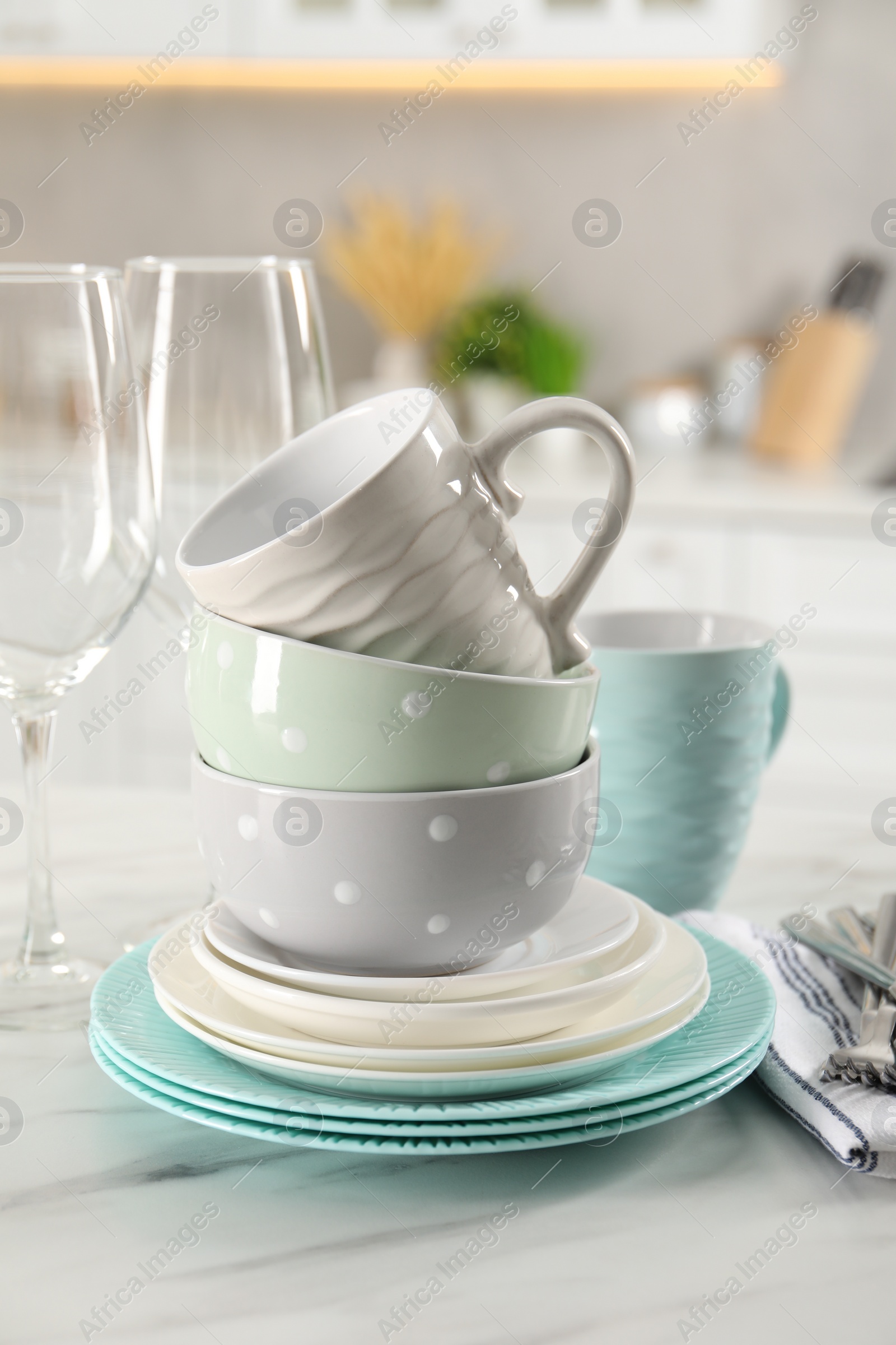 Photo of Many different clean dishware and cups on white marble table in kitchen