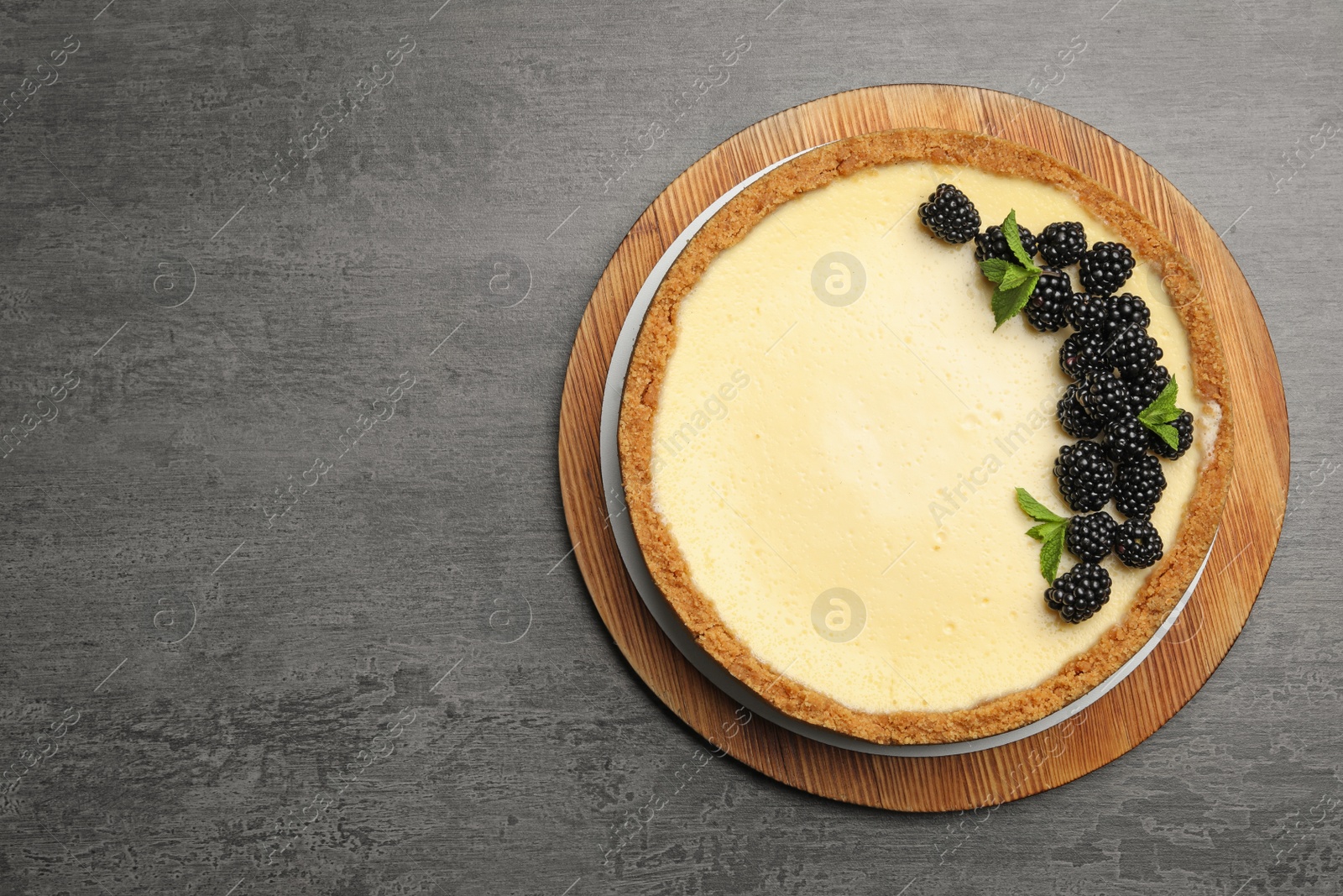 Photo of Delicious cheesecake decorated with blackberries on grey table, top view. Space for text