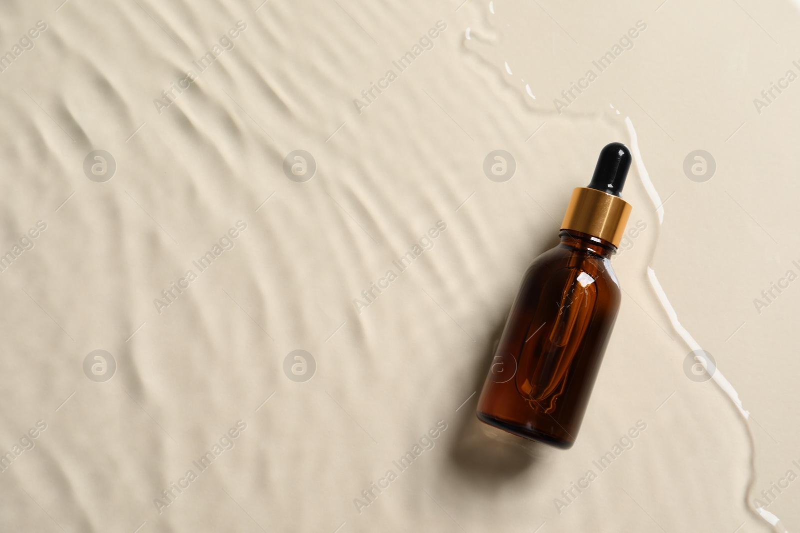 Photo of Bottle of cosmetic oil in water on beige background, top view. Space for text