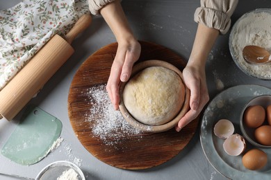 Woman making dough at grey table, top view