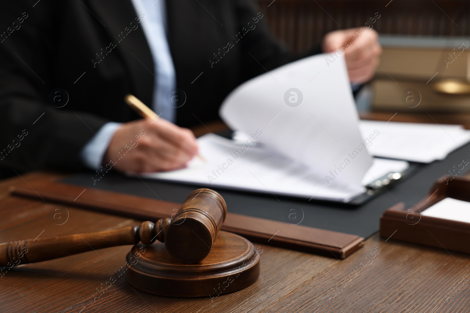 Photo of Lawyer working with documents at wooden table indoors, focus on gavel