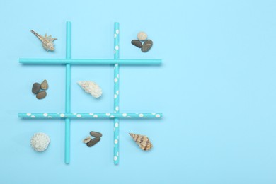 Tic tac toe game made with sea treasures on light blue background, top view