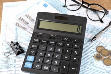 Photo of Tax accounting. Calculator, documents, money, glasses and pen on table, closeup