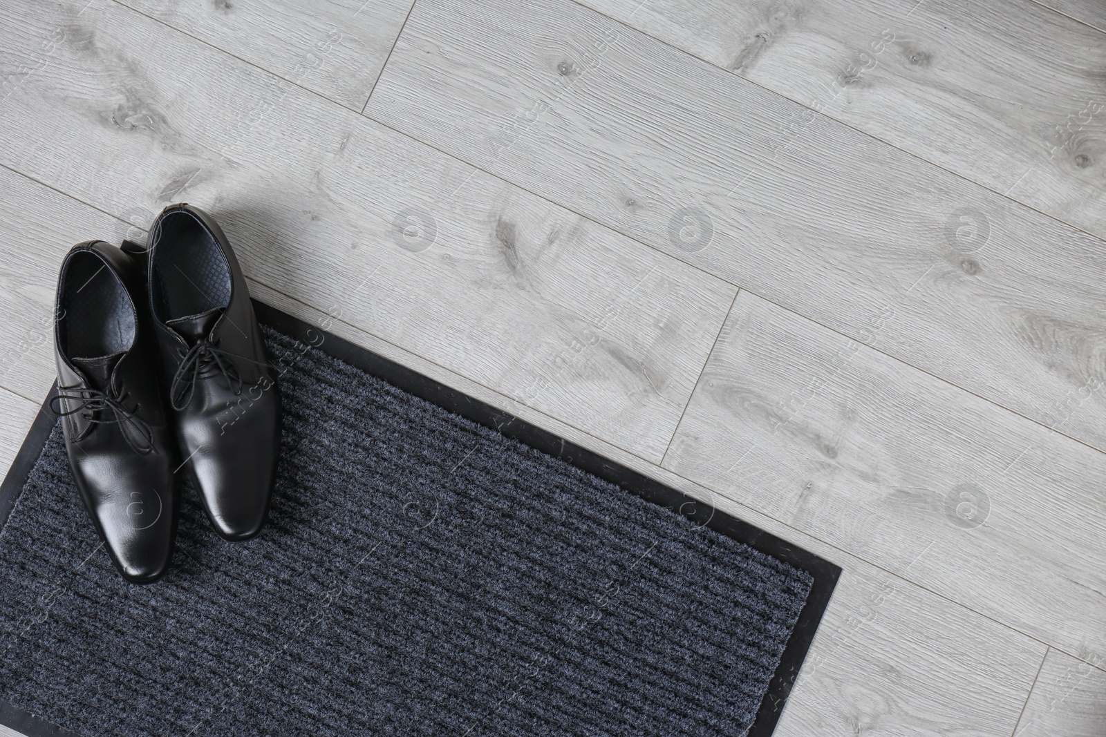 Photo of Door mat and shoes on floor, top view. Space for text