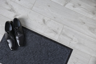 Door mat and shoes on floor, top view. Space for text