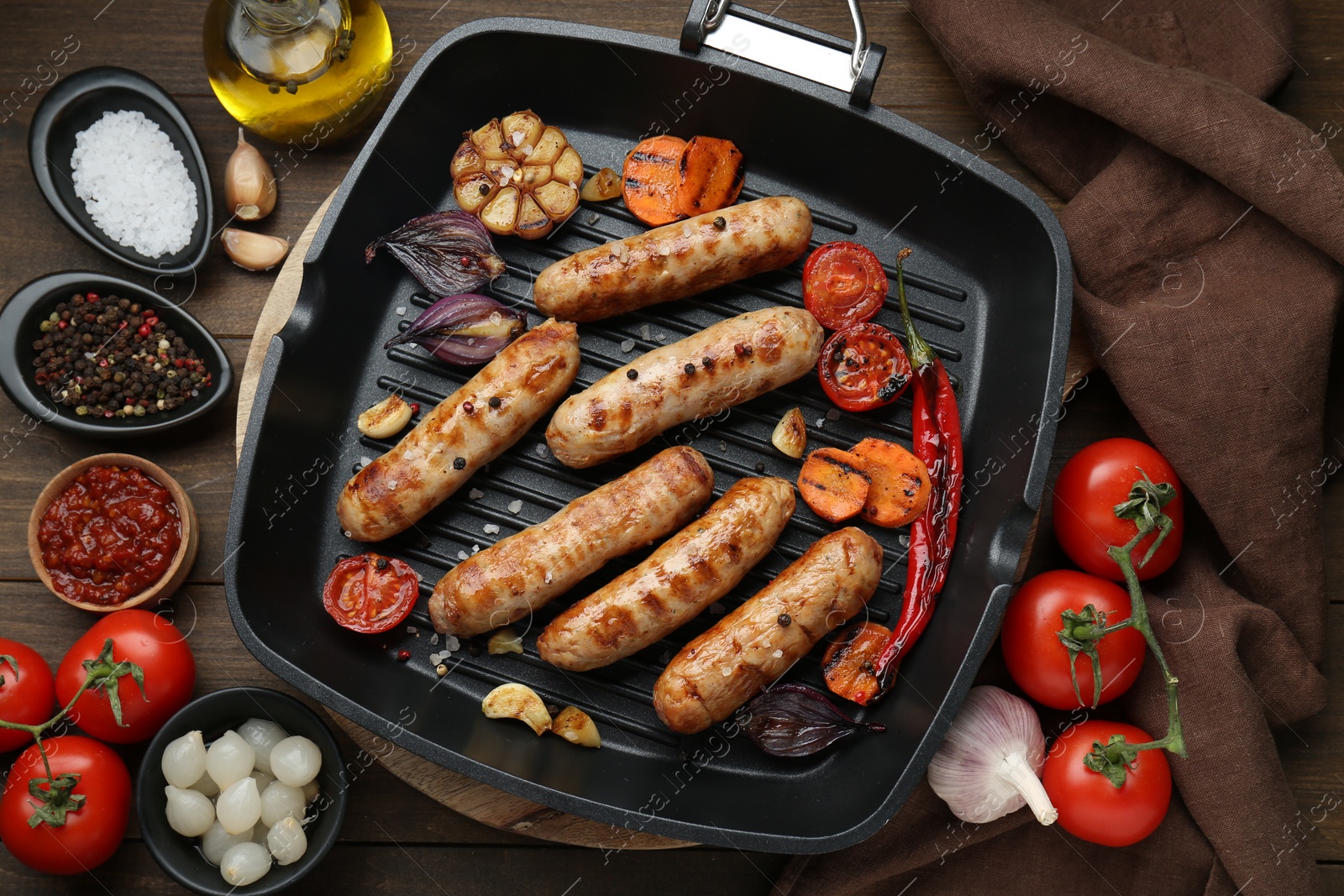 Photo of Tasty grilled sausages and ingredients on wooden table, flat lay