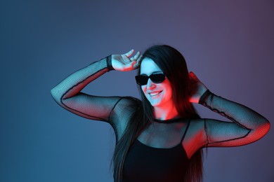 Photo of Portrait of beautiful young woman with sunglasses on color background