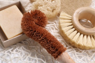 Photo of Cleaning brushes, loofah and soap bar on table, closeup