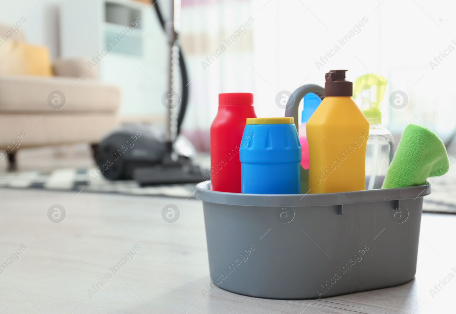 Photo of Basin with different detergents on floor indoors, space for text. Cleaning service