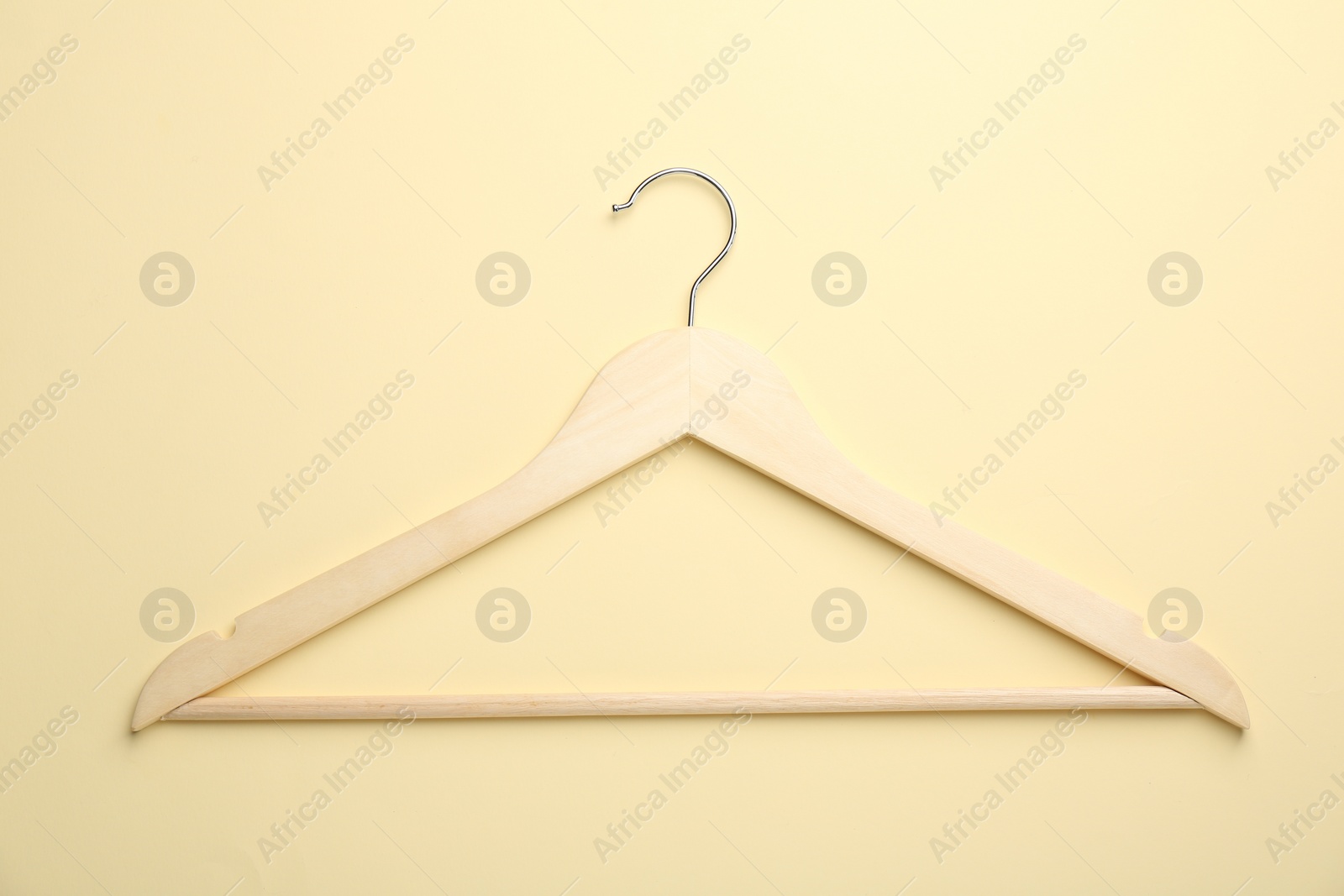 Photo of Wooden hanger on pale yellow background, top view