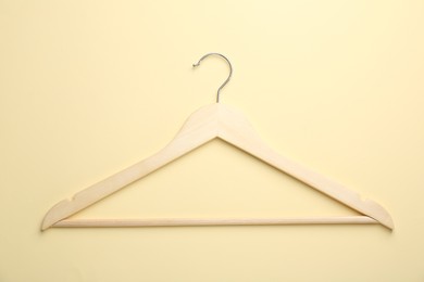 Wooden hanger on pale yellow background, top view