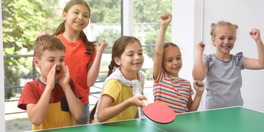 Image of Cute happy children playing ping pong indoors. Banner design
