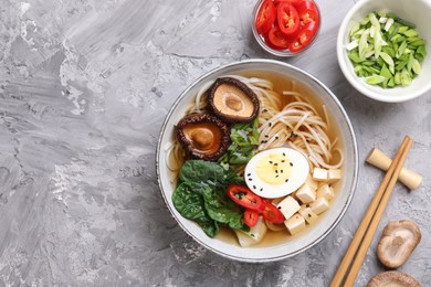 Delicious vegetarian ramen served on grey table, flat lay with space for text. Noodle soup