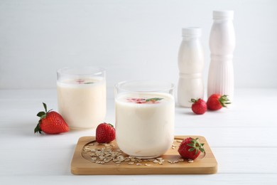 Tasty yogurt, oats and strawberries on white wooden table