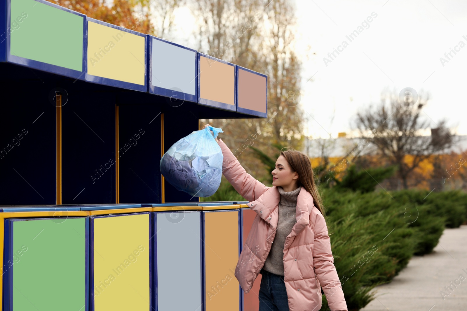 Photo of Woman throwing garbage into bin at recycling point outdoors