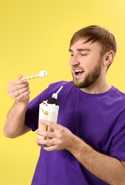 Young man with glass of delicious milk shake on color background