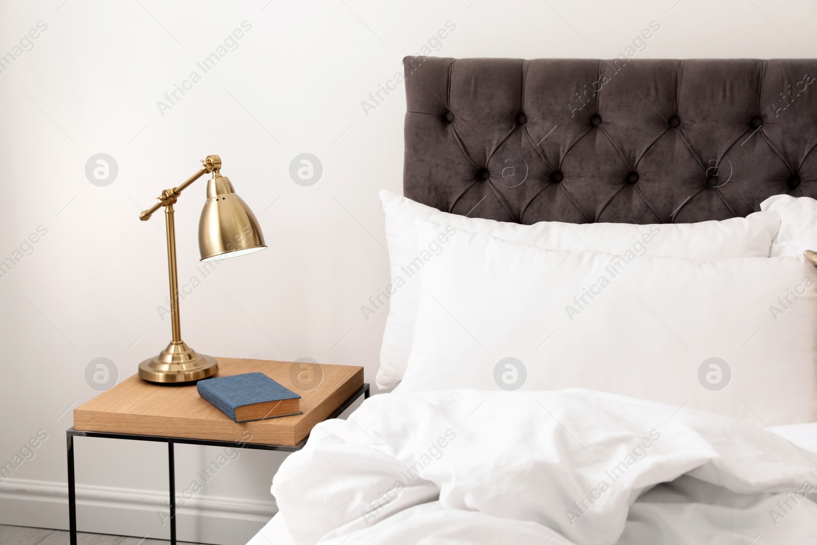 Photo of Comfortable bed and nightstand in modern room interior