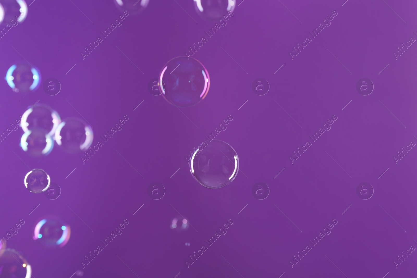 Photo of Beautiful transparent soap bubbles on violet background, space for text