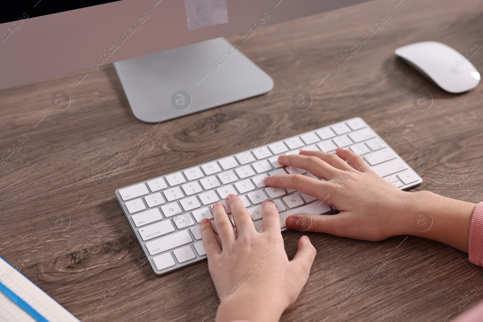 Photo of E-learning. Girl using computer during online lesson at table indoors, closeup