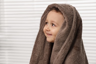Photo of Cute little boy wrapped with towel after washing hair in bathroom