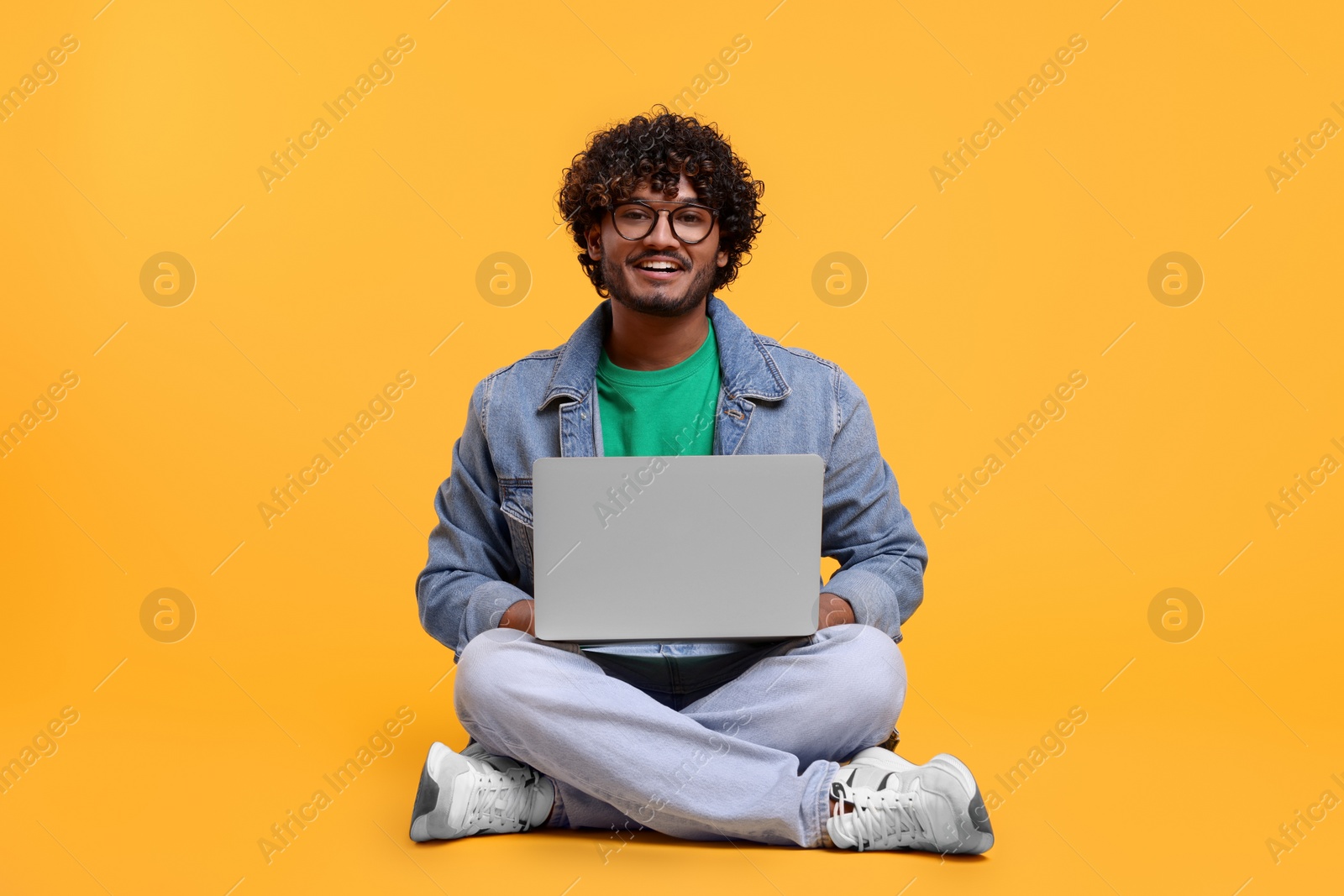 Photo of Smiling man with laptop on yellow background