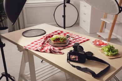 Photo of Professional camera and composition with tasty sandwich on table in photo studio. Food photography